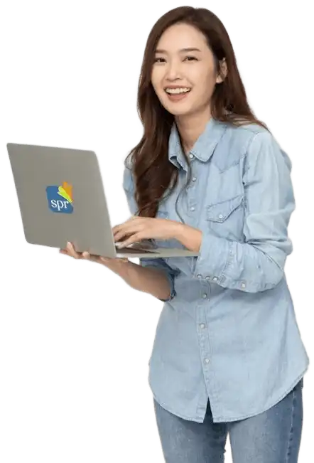Smiling woman in a light denim shirt holding an SPR-branded laptop while standing against a white background