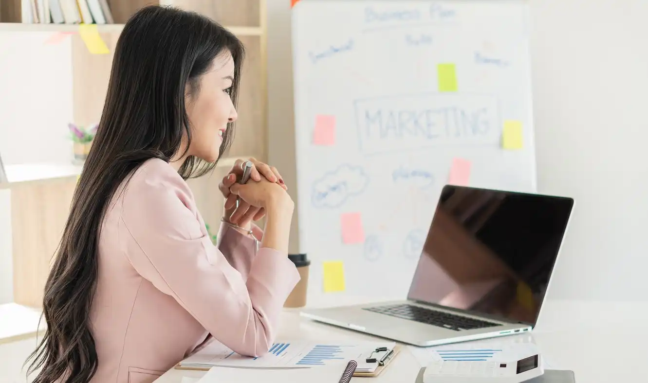 Young business woman working on financial graph analysis on desk with laptop and calculator.