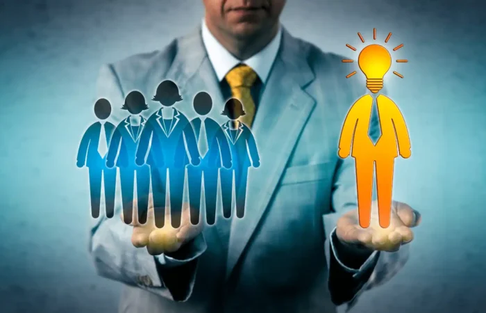 Business professional holding icons of a team and a standout candidate with a lightbulb symbol for leadership potential
