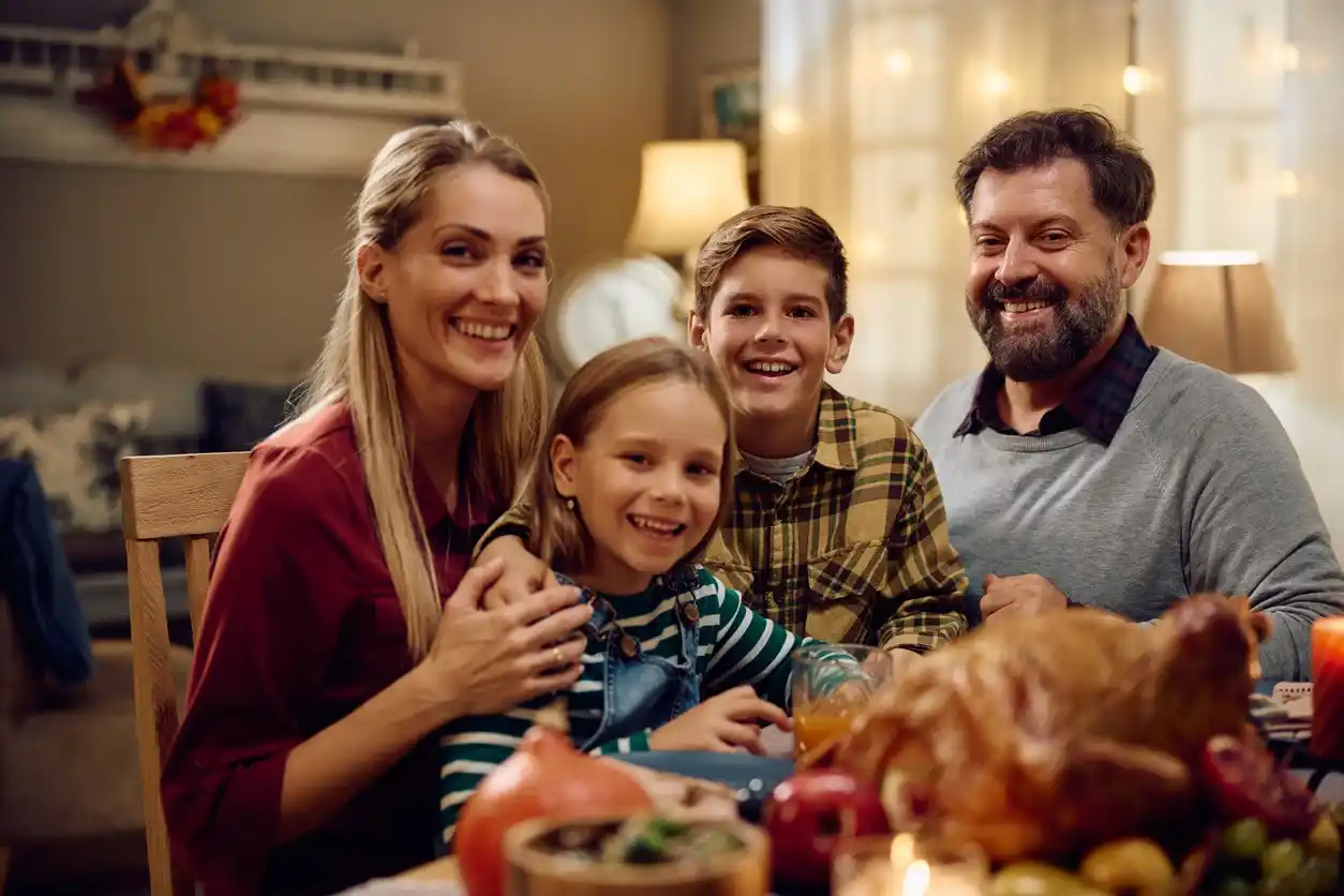 Happy family on Thanksgiving in dining room looking at camera.